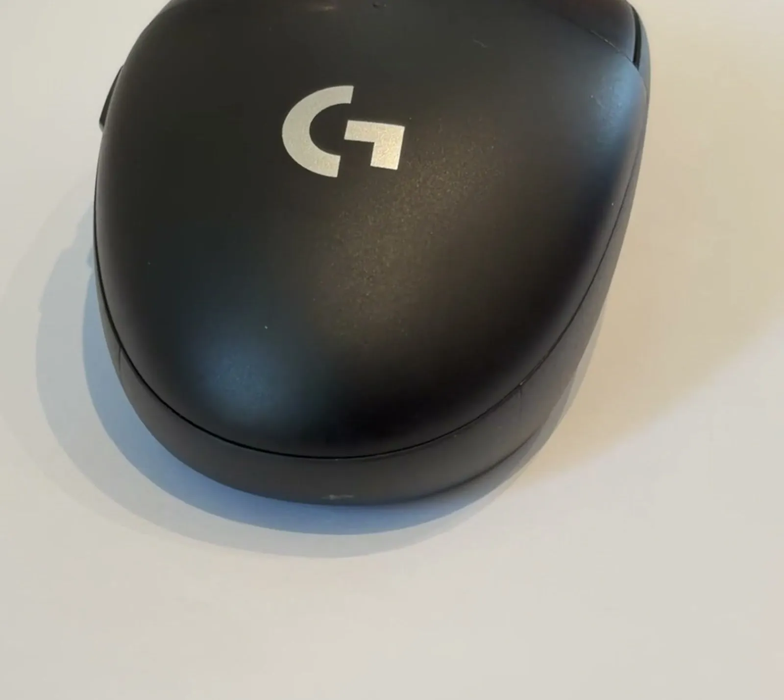 로지텍 G304 무선 마우스를 낮은 각도에서 본 모습, 무광 검정 바디에 흰 G 로고