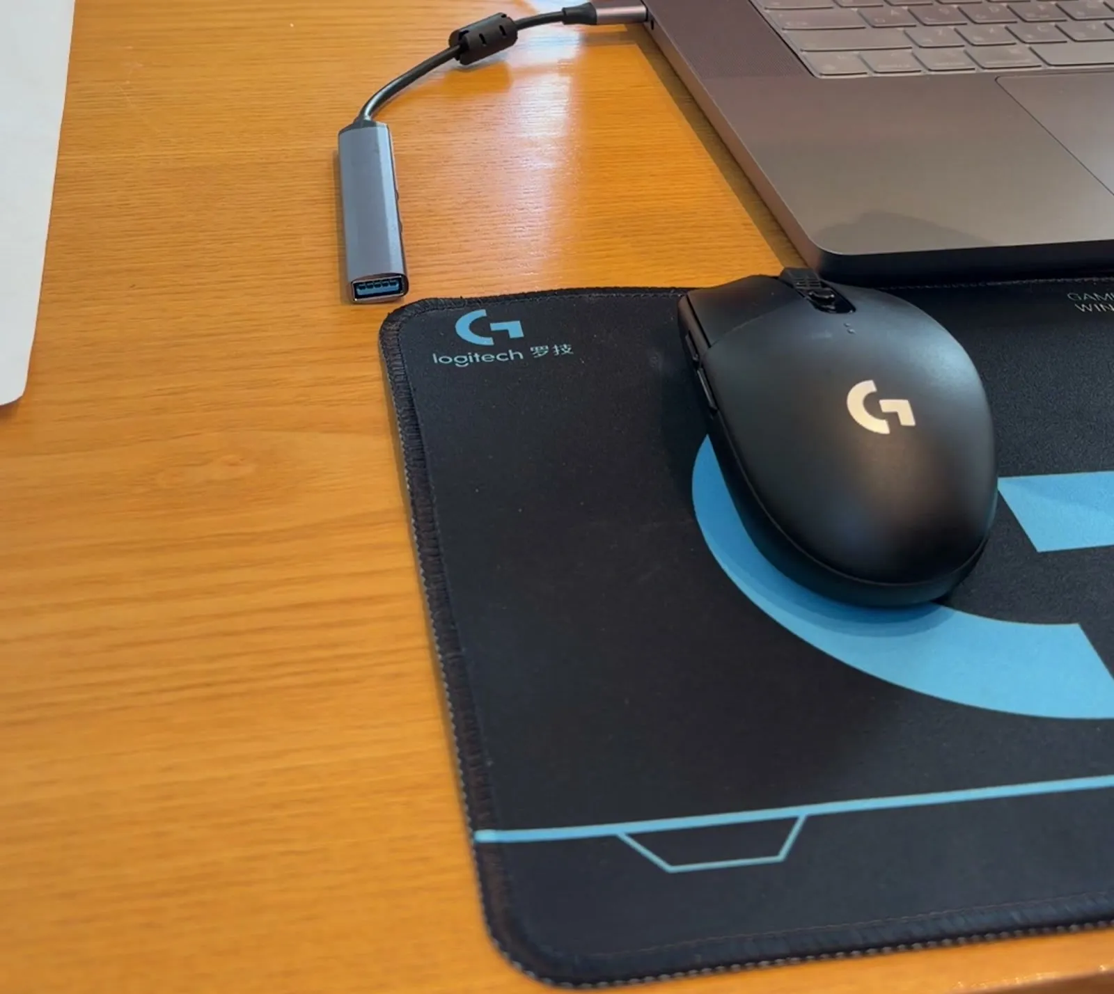 맥북 옆에 USB-C to USB-A 어댑터가 연결돼 있고, 마우스패드 위에 G304가 놓인 모습
